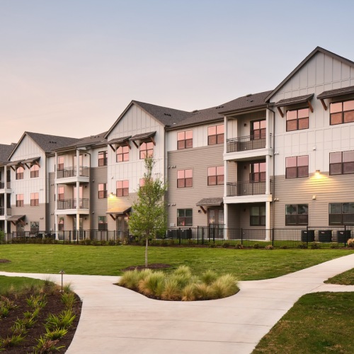 Welcome home a row of apartments at dusk with a walkway and grass