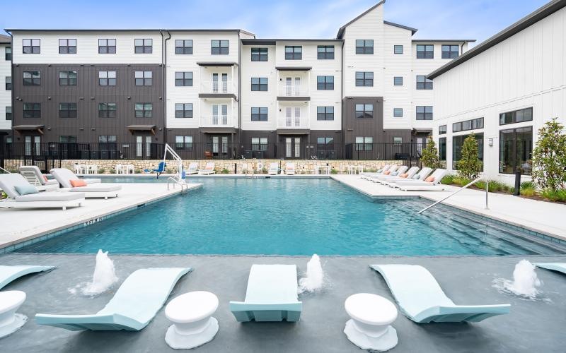 a pool with lounge chairs and a building in the background