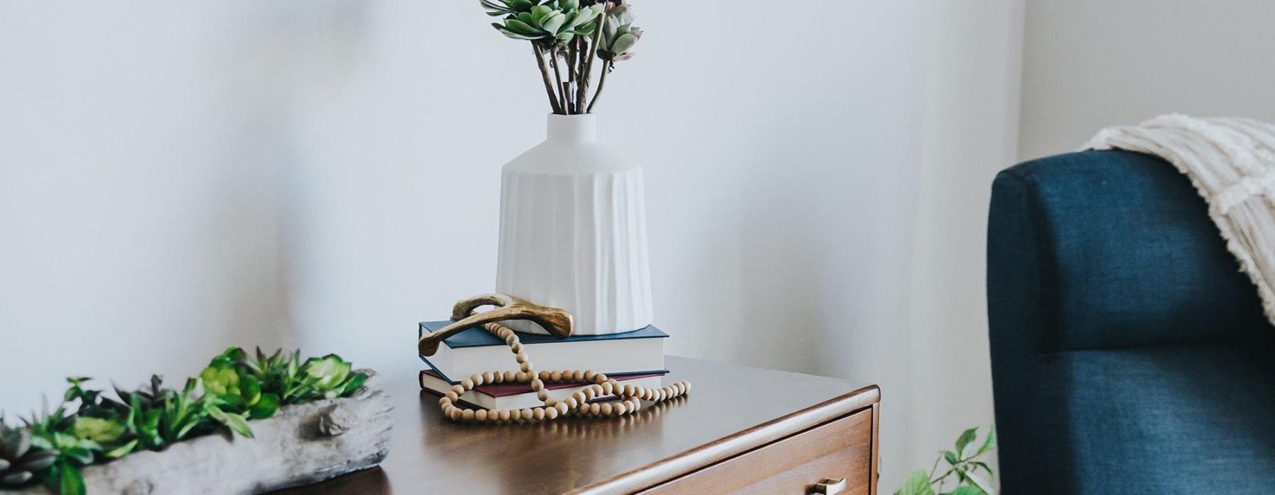 a dresser with a vase of plants on top